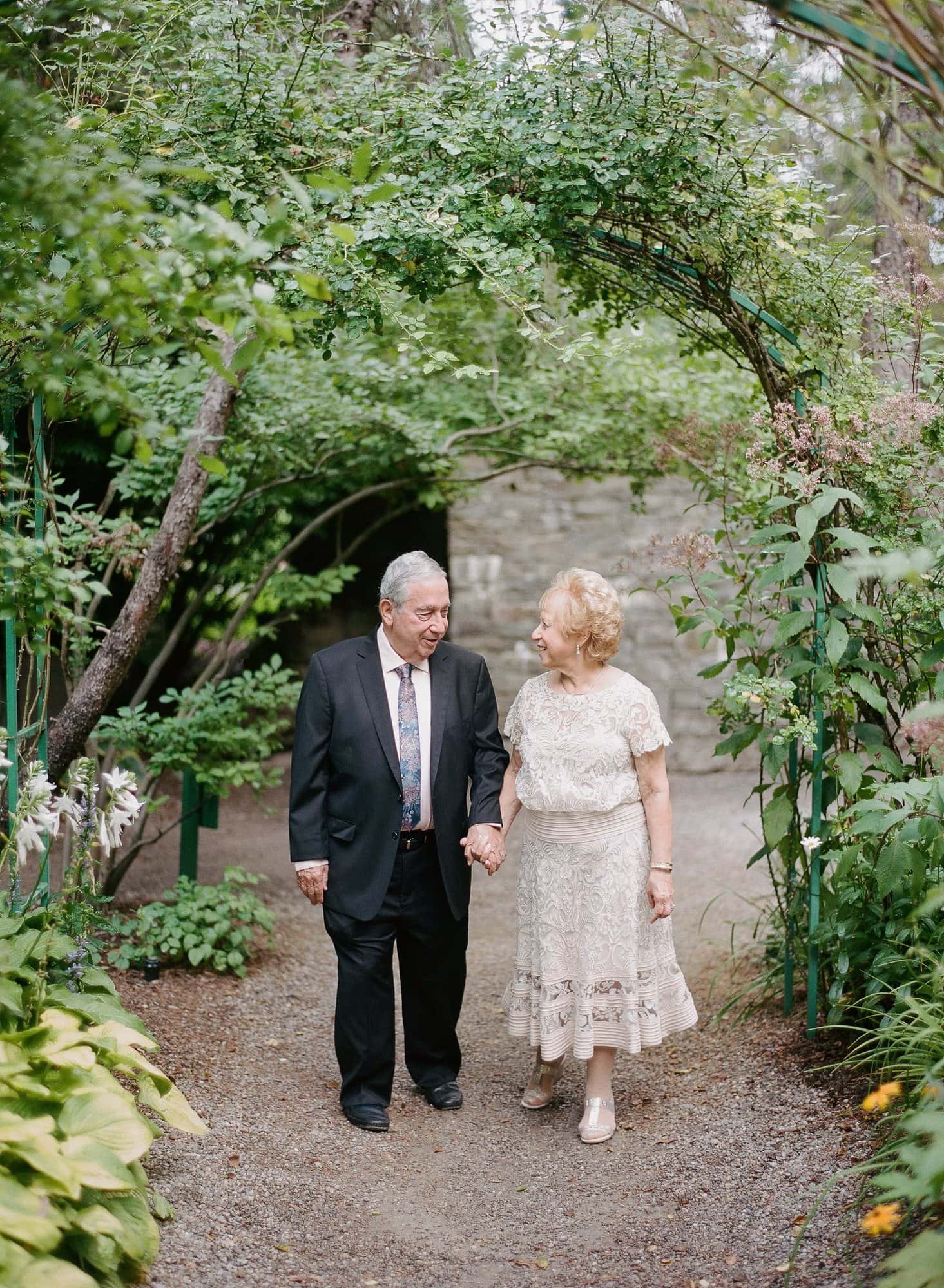 A couple walking together under a garden arch at Grounds for Sculpture during their vow renewal