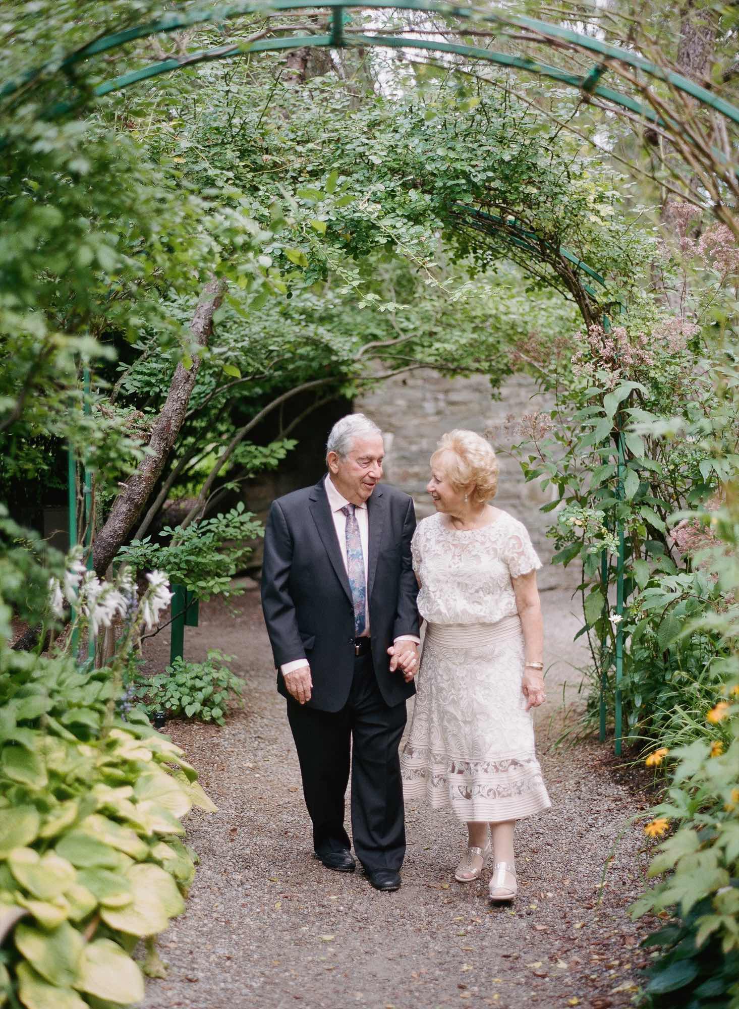 An older couple standing together under a garden arbor at Grounds for Sculpture, photographed on film