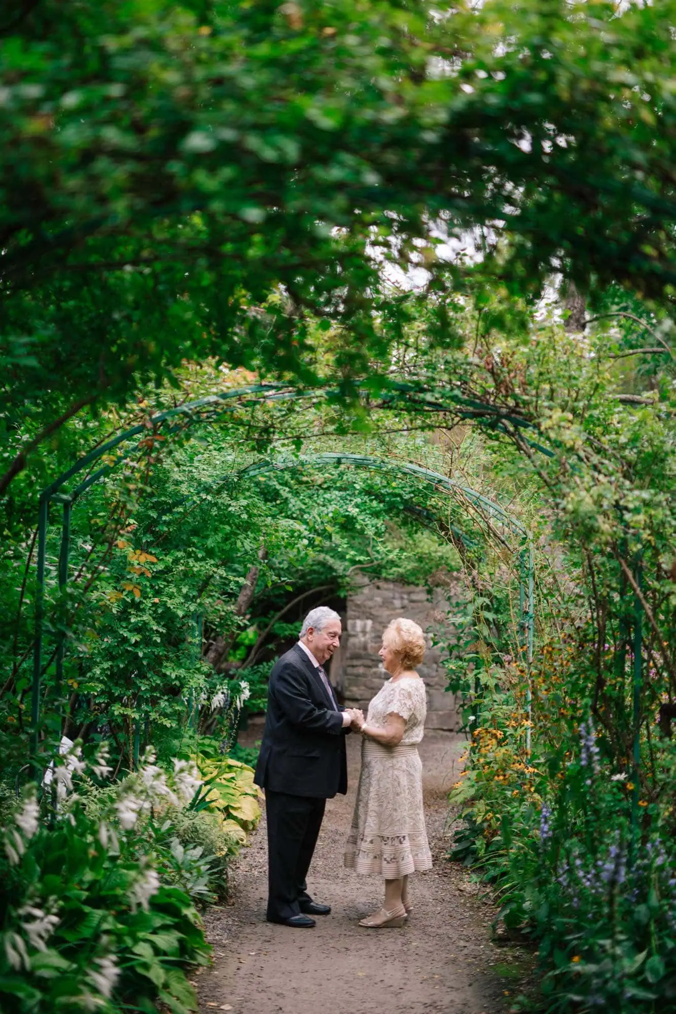 An older couple holding hands under a wooden arbor at Grounds for Sculpture in Hamilton, New Jersey
