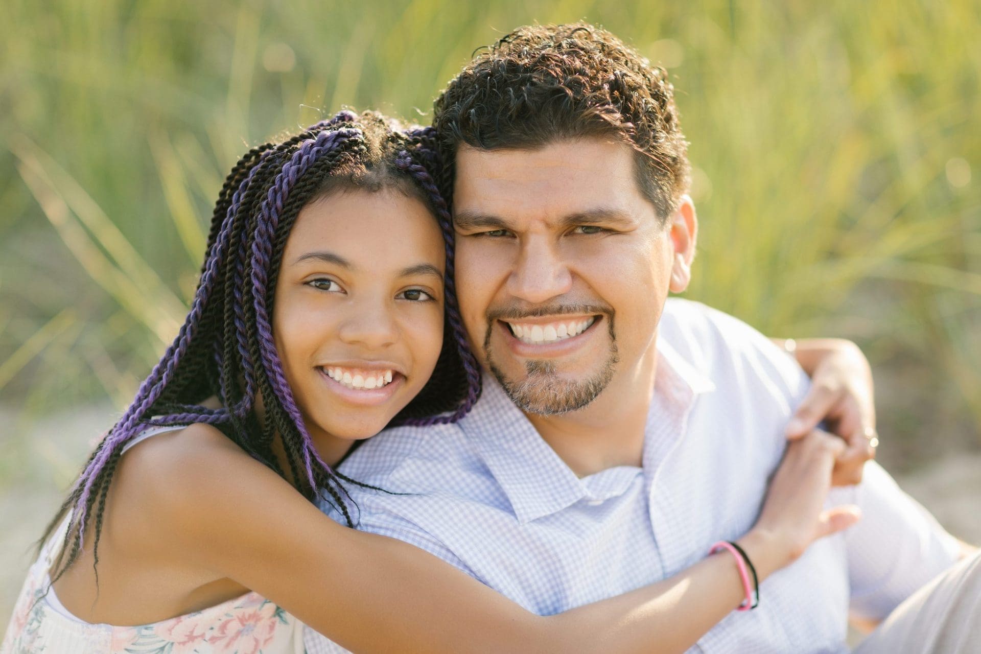 A daughter hugging her father from behind, cheek to cheek, during a Long Beach Island family session