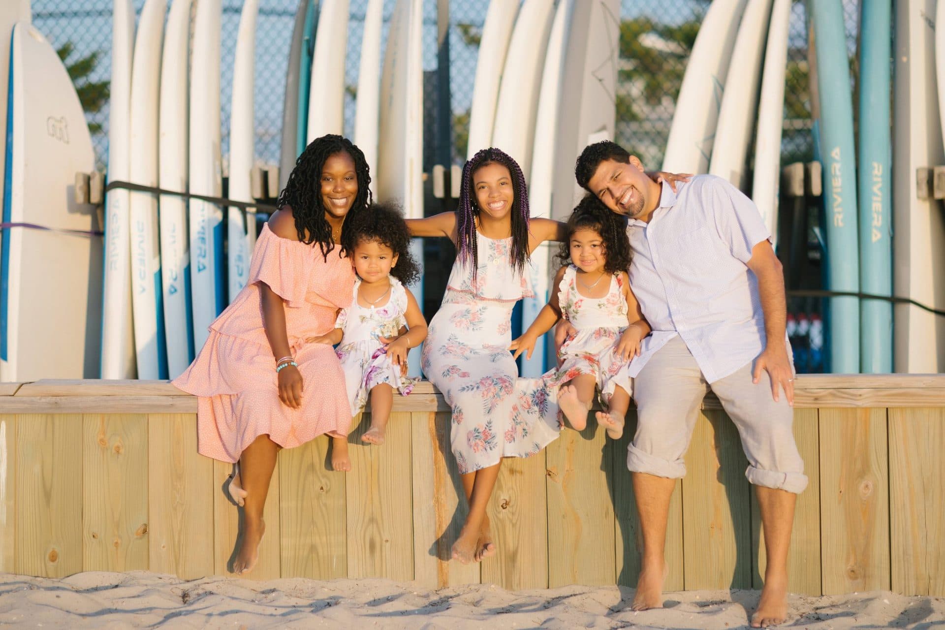 A family of five on a bulkhead in front of the surfboard rack at a Beach Haven bay beach