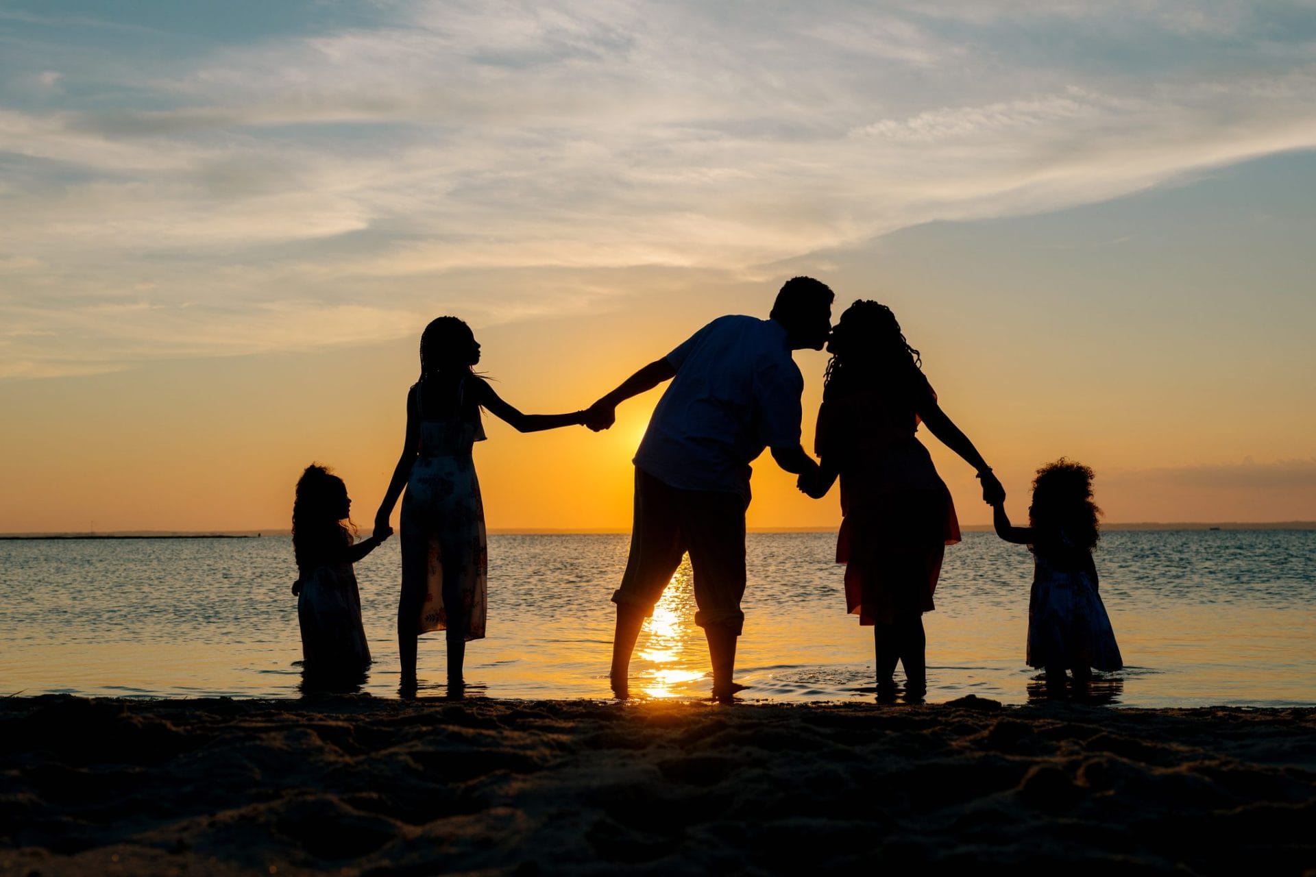 A family of five in silhouette with the sun at the waterline during a Long Beach Island session
