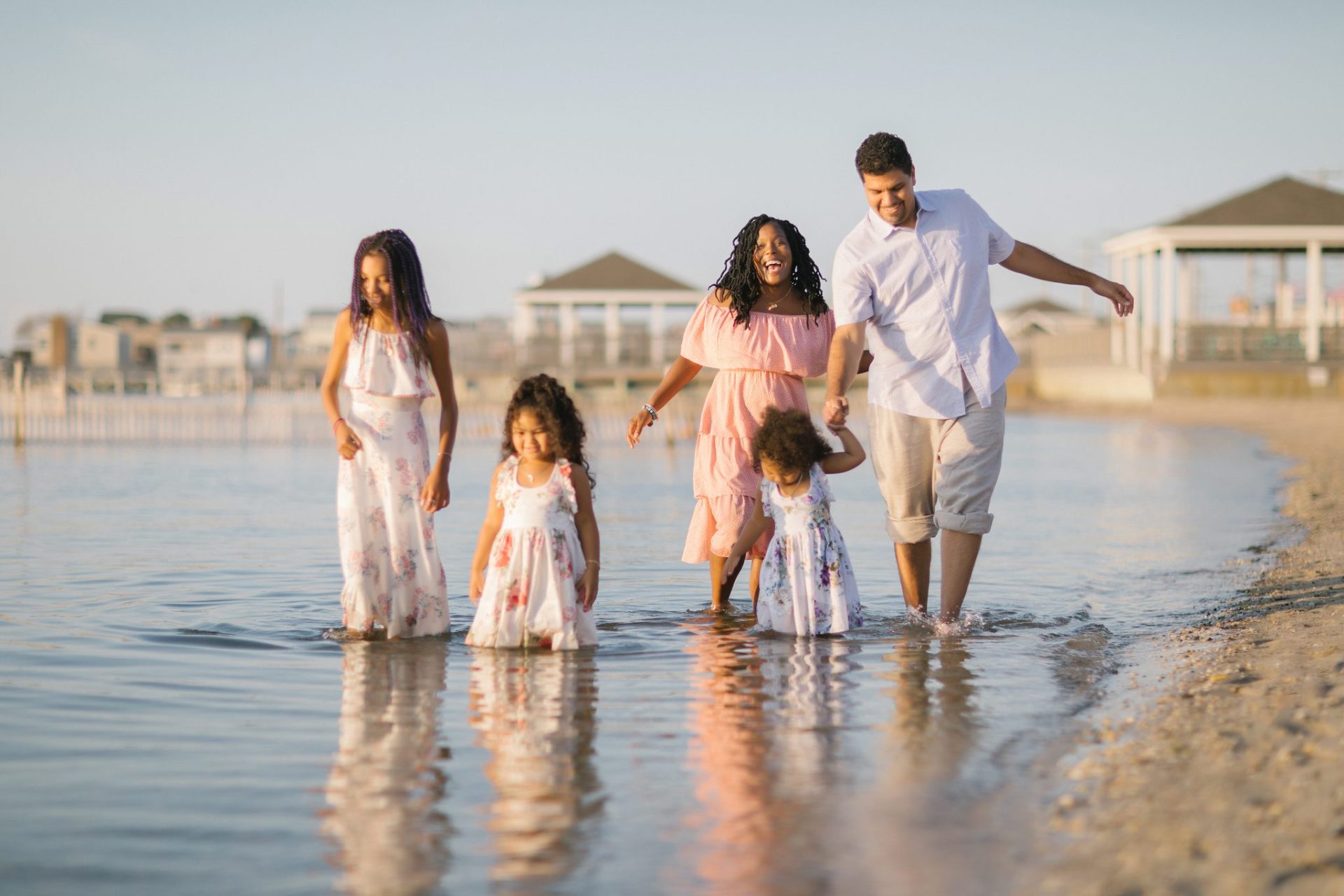 A family of five wading through the shallow bay water during a Beach Haven family session
