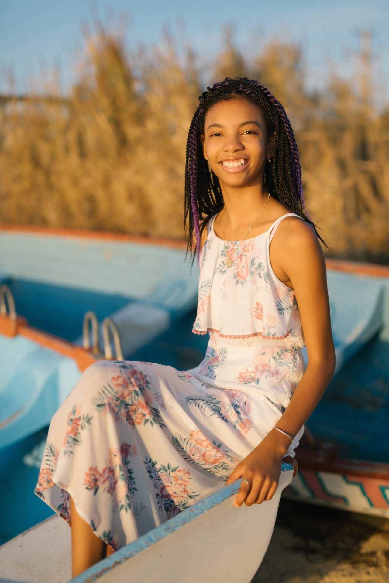A girl sitting on the edge of a rowboat with gold reeds behind her on Long Beach Island