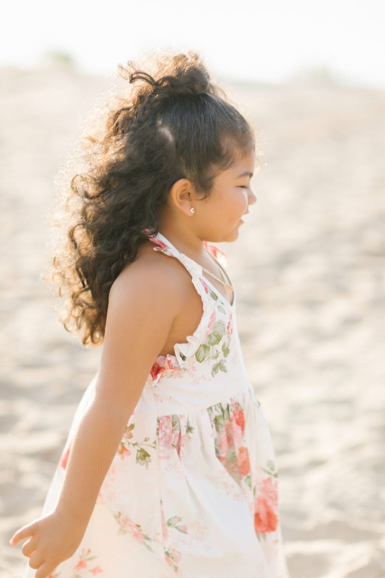 A young girl walking across the sand with her hair up during a Long Beach Island family session