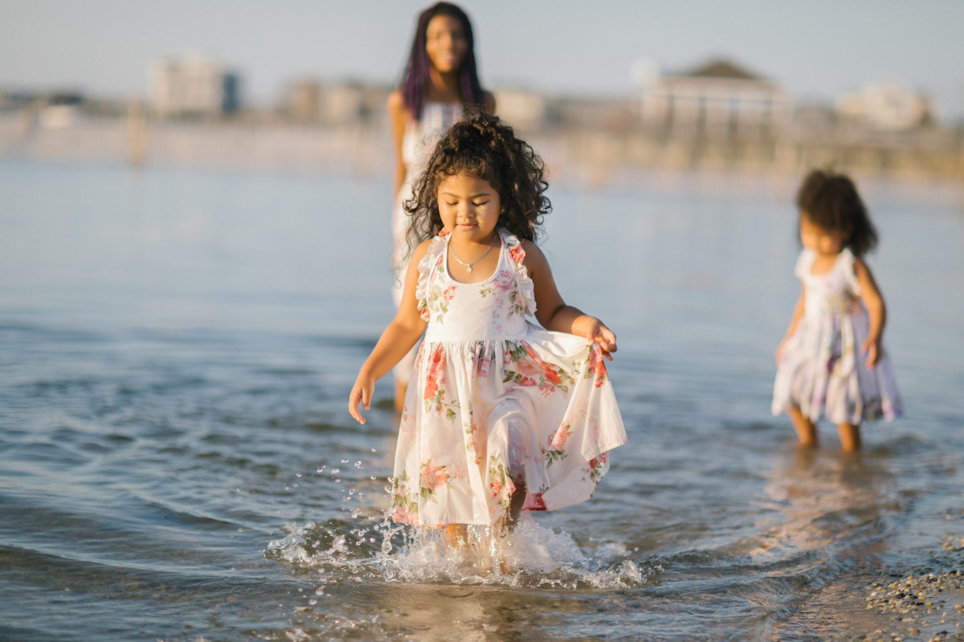 A girl holding up her dress as she walks through the shallow bay water on Long Beach Island