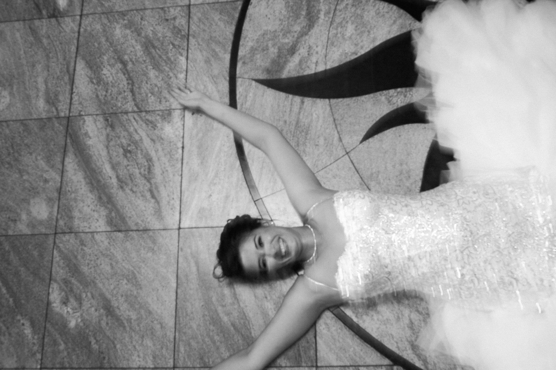 Bride lying on the dance floor laughing with her dress fanned around her