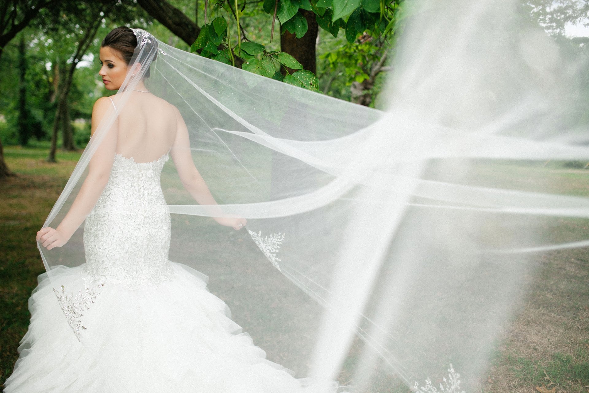 Bride looking back over her shoulder as her veil lifts