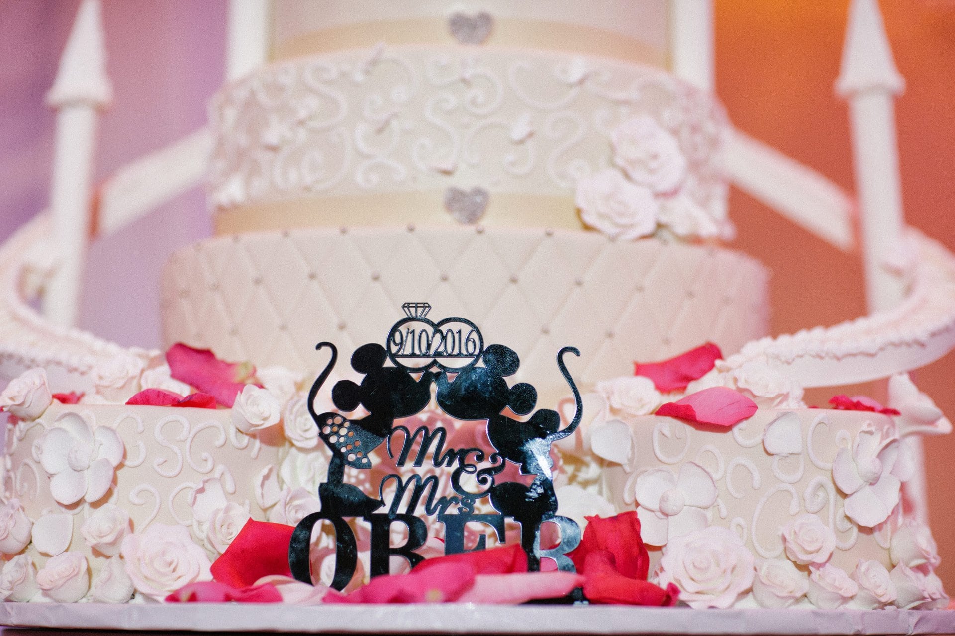 Close detail of the wedding cake topper and rose petals