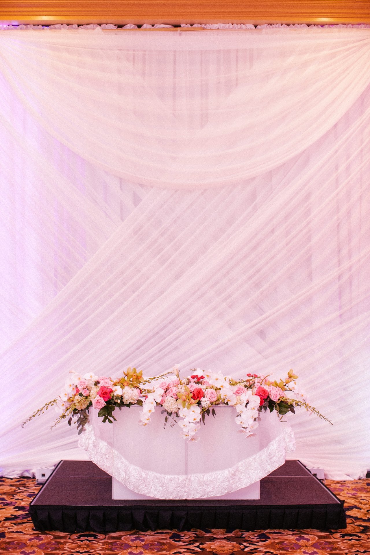 Altar drape and floral arrangement at the head of the ceremony aisle