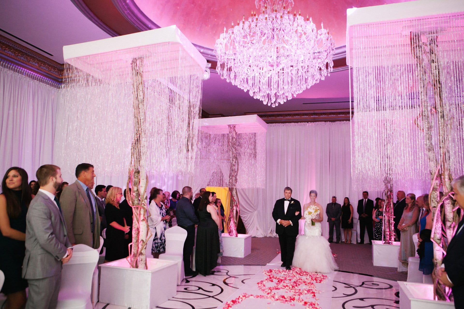 Guests standing as the ceremony begins under the crystal strand canopies