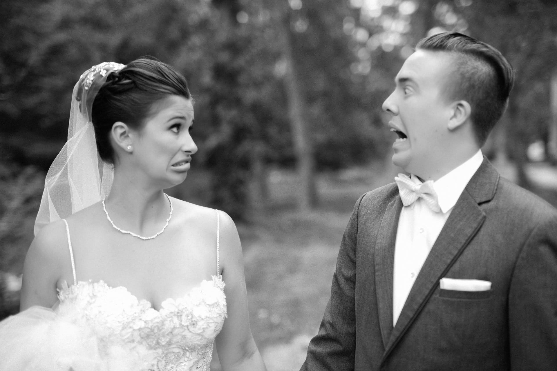 Bride and groom pulling faces at each other in black and white