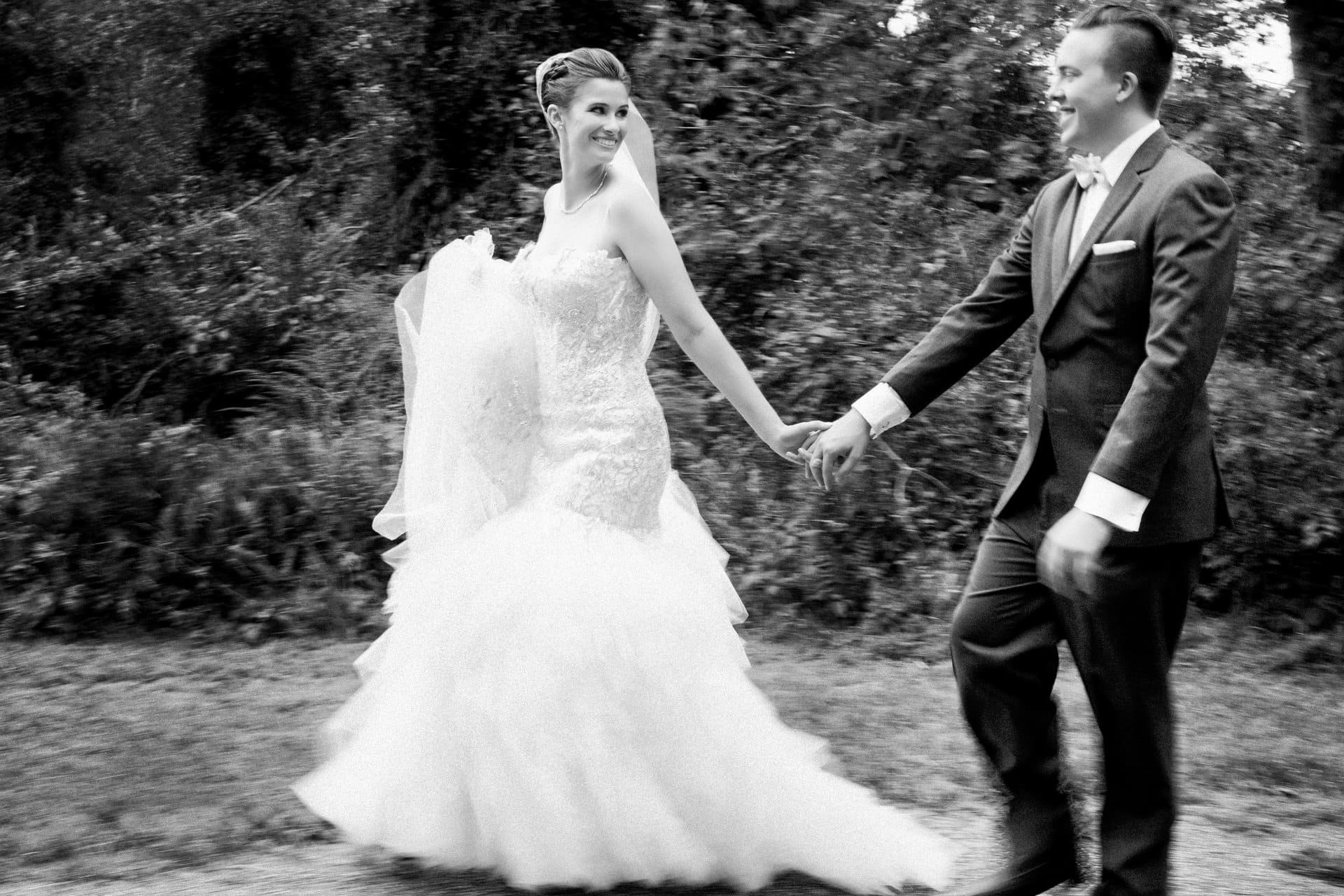 Bride and groom walking away together, full skirt trailing