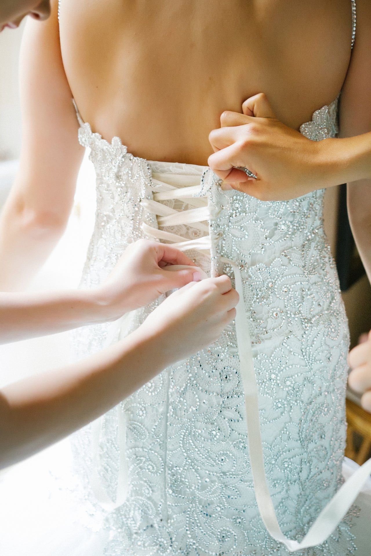 Corset back of a lace wedding gown being laced up