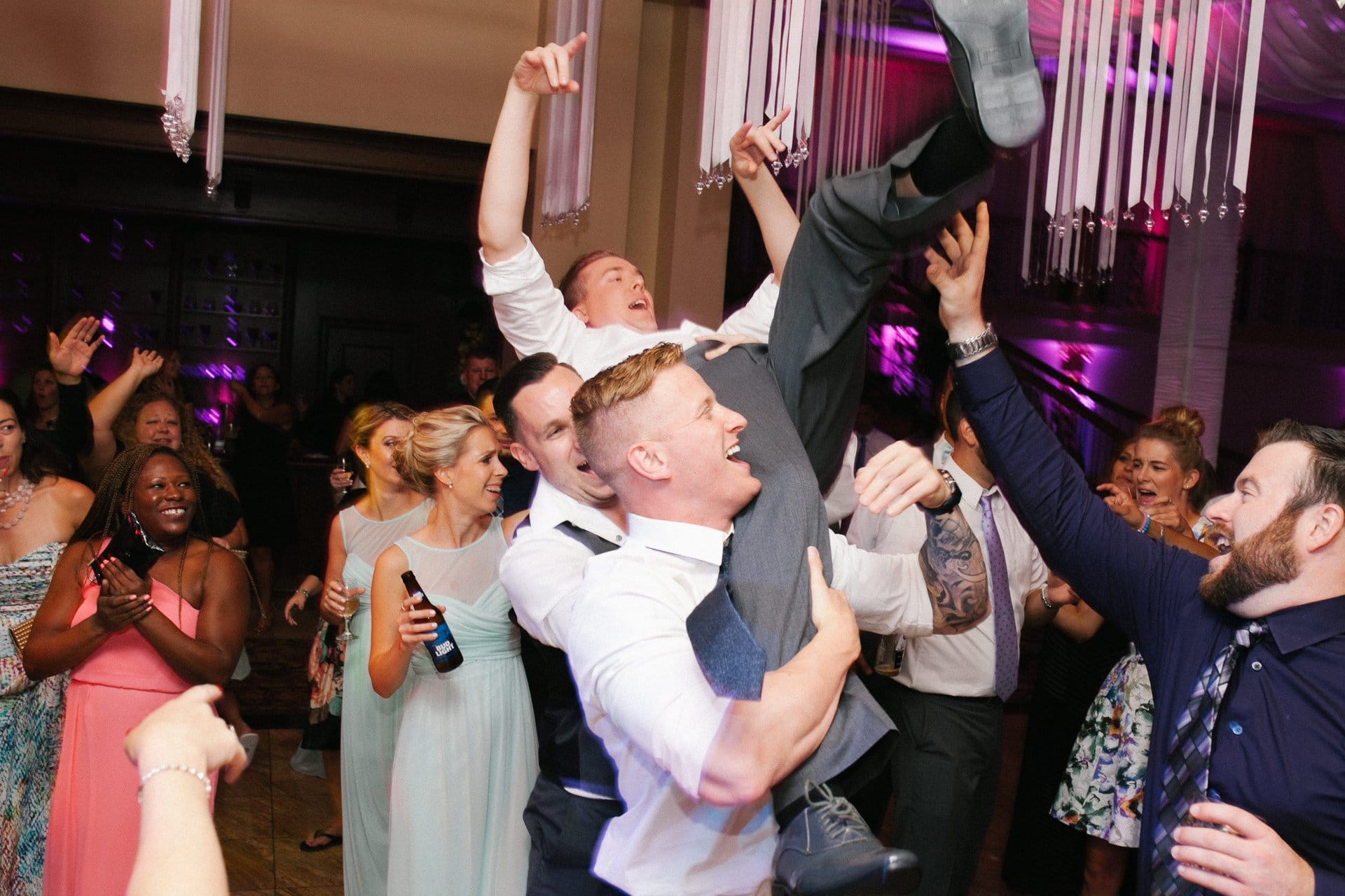 Groomsmen lifting the groom over the dance floor