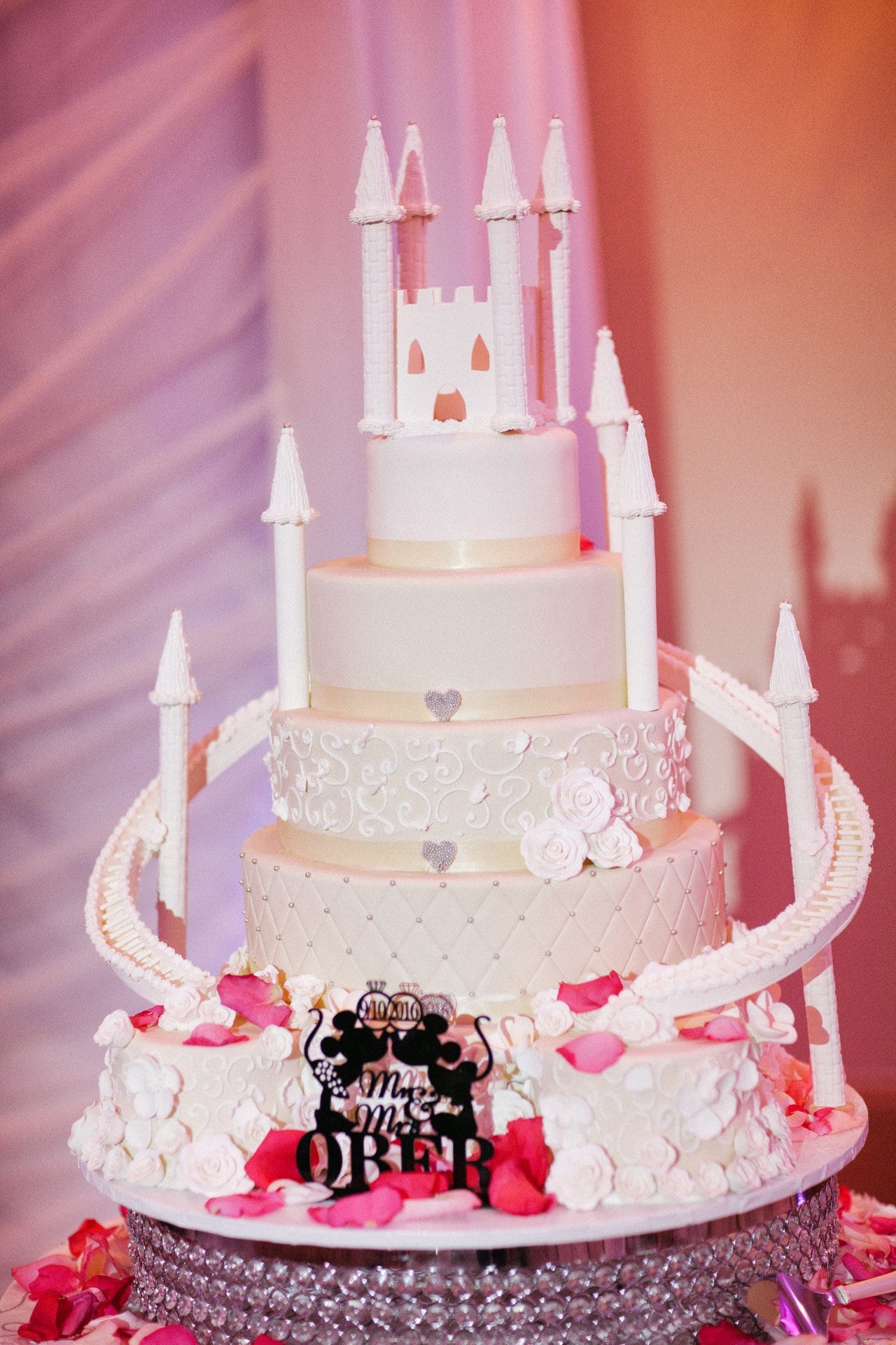 Tiered white wedding cake with a castle topper