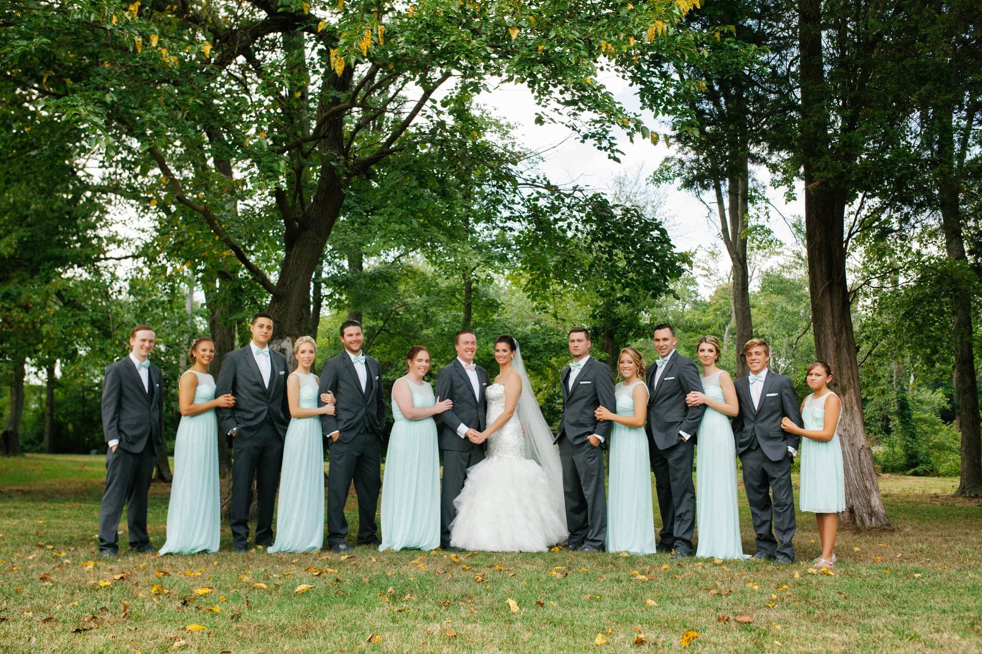 Full wedding party lined up under the trees at Berlin Park