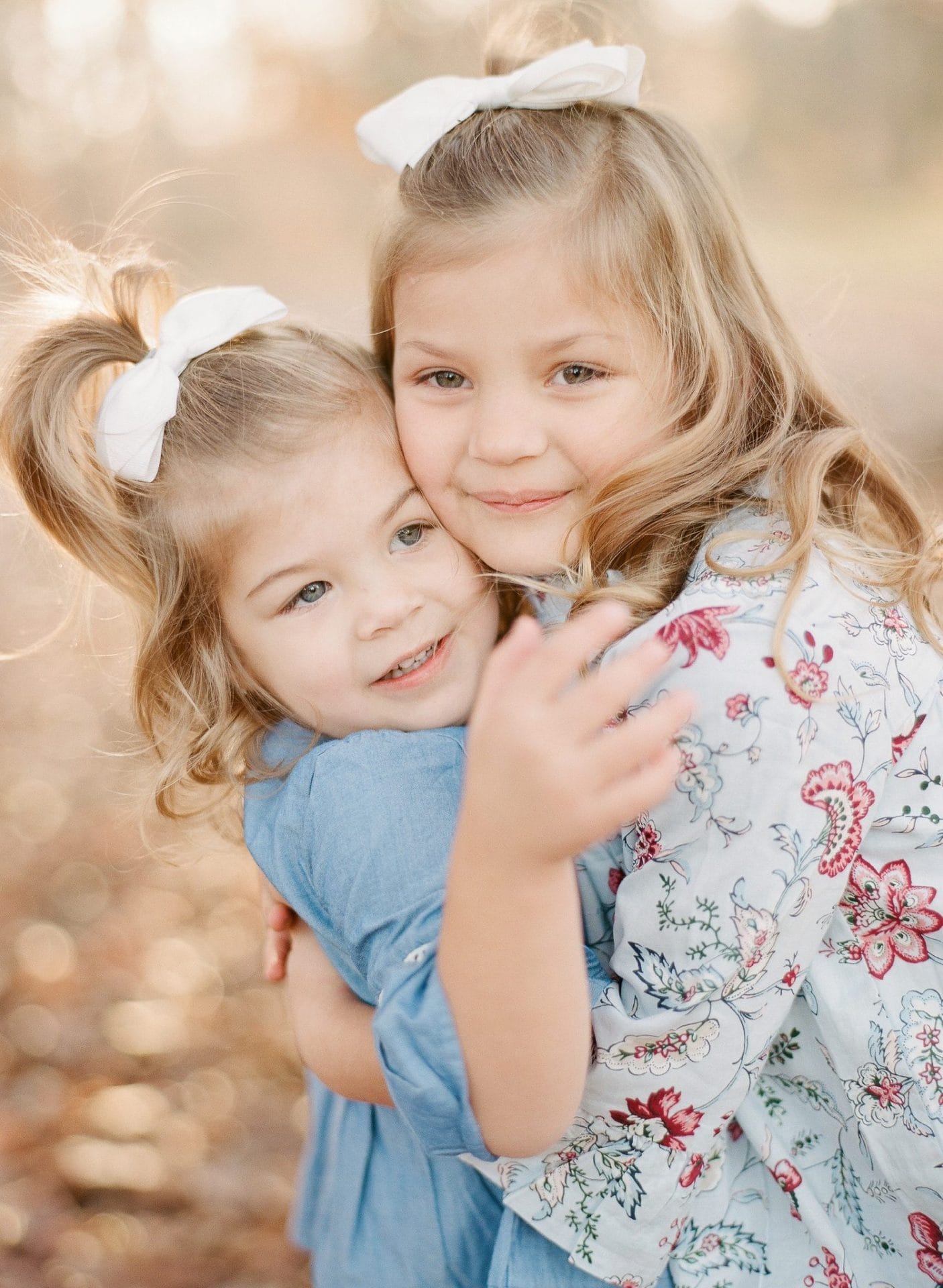 A young girl and her little sister with their cheeks pressed together in the autumn woods in Medford, New Jersey