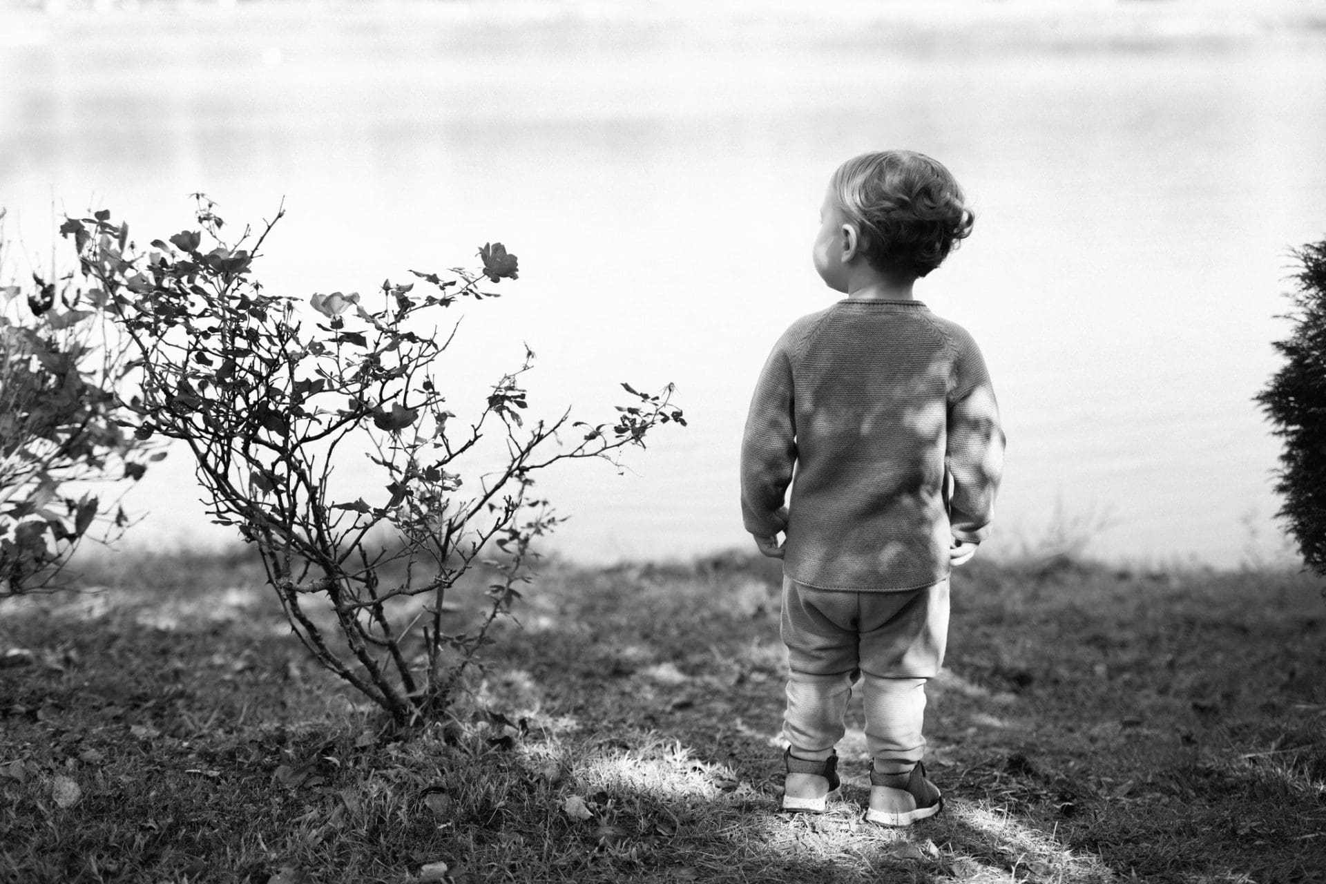 A black and white photograph of a small boy standing at the edge of the lake at Laurel Acres Park in Mount Laurel, New Jersey
