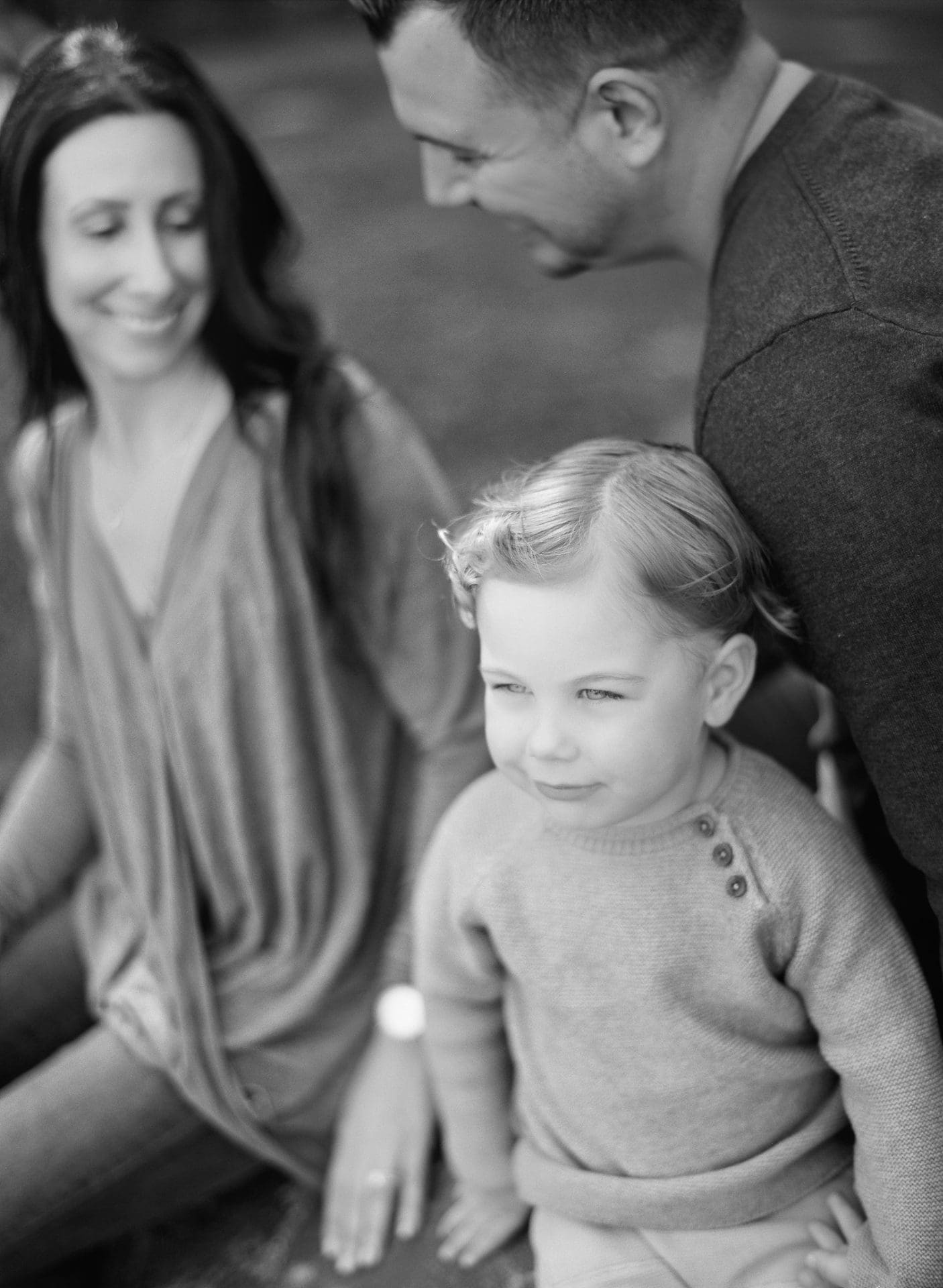 A black and white photograph of a mom and dad sitting on the grass with their son at Laurel Acres Park in Mount Laurel, New Jersey