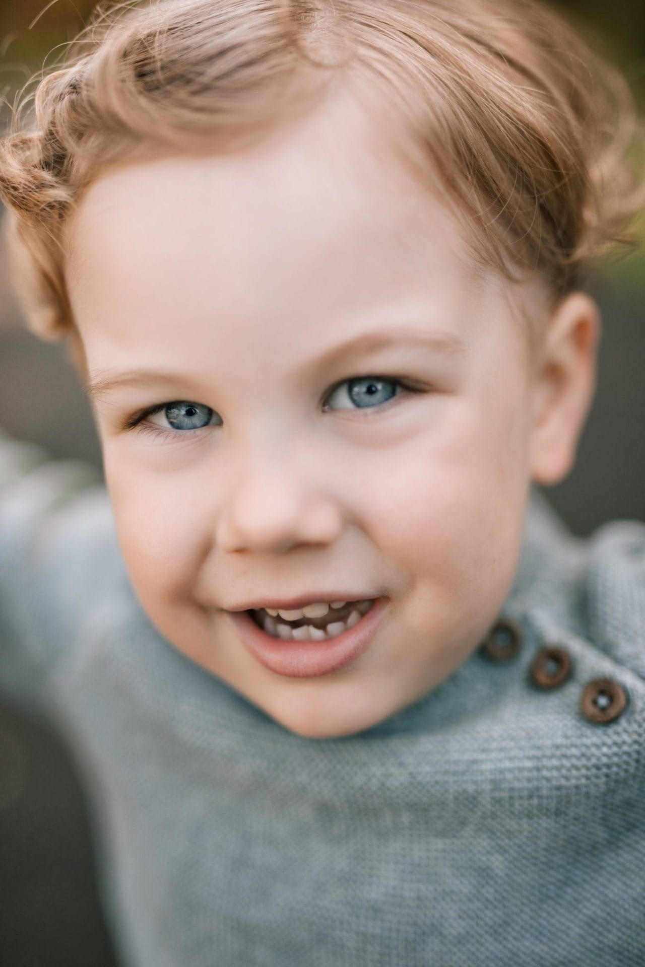 A close portrait of a blue eyed boy smiling during a family session at Laurel Acres Park in Mount Laurel, New Jersey