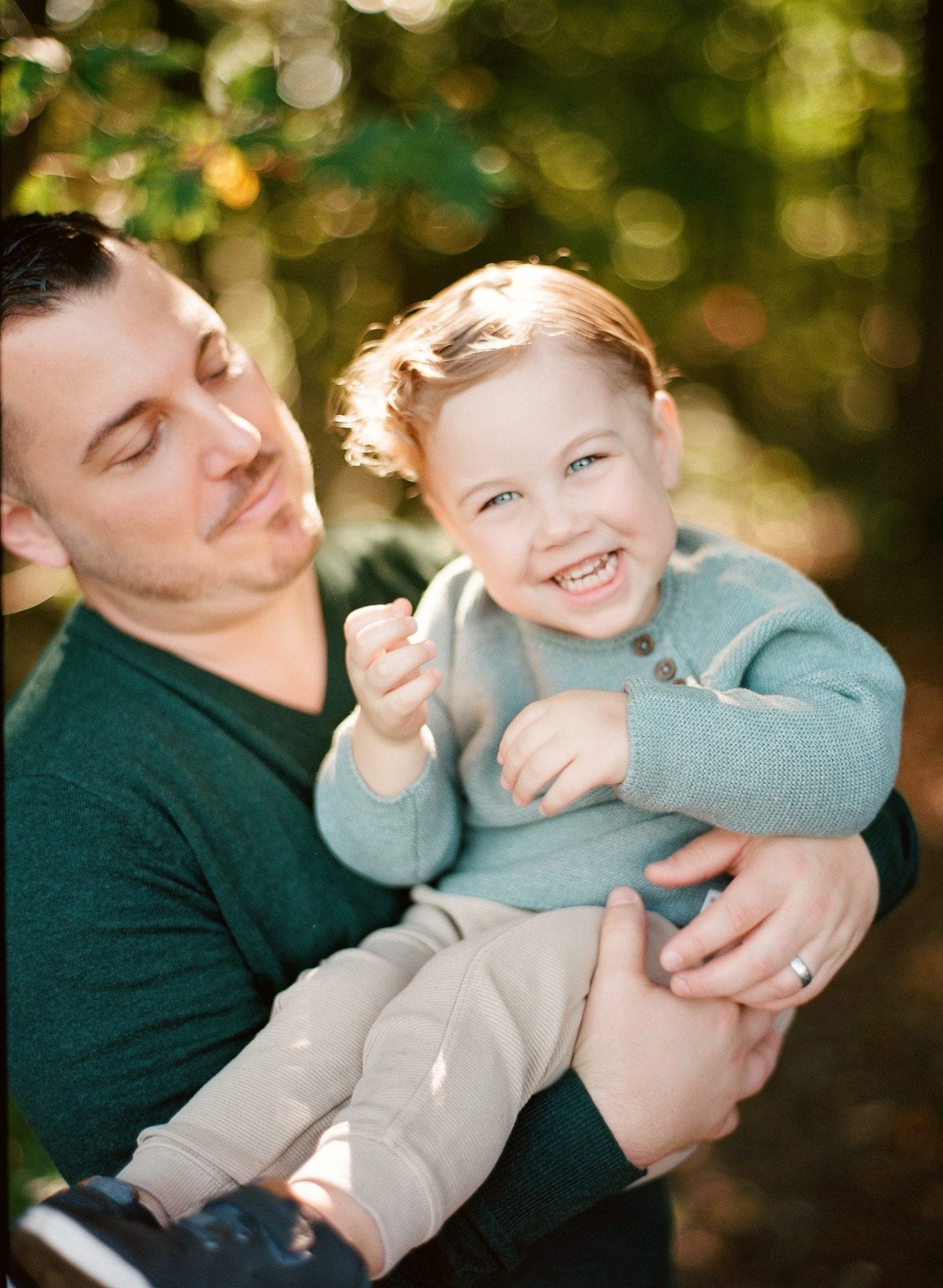 A dad holding his laughing son during a family session in the woods at Laurel Acres Park in Mount Laurel, New Jersey