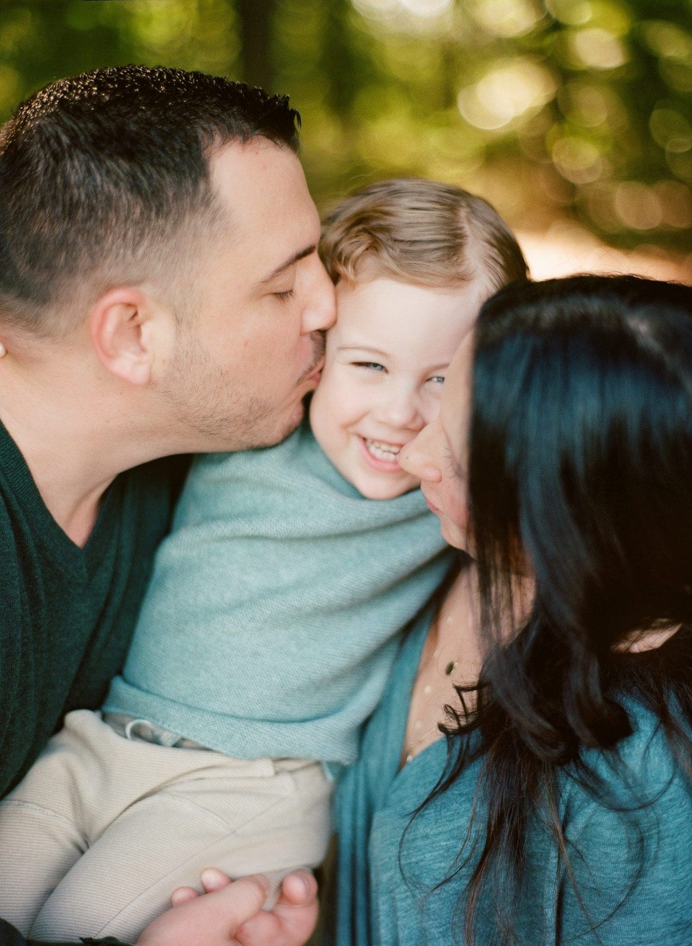 A dad kissing his sons cheek while his mom leans in beside them in Mount Laurel, New Jersey
