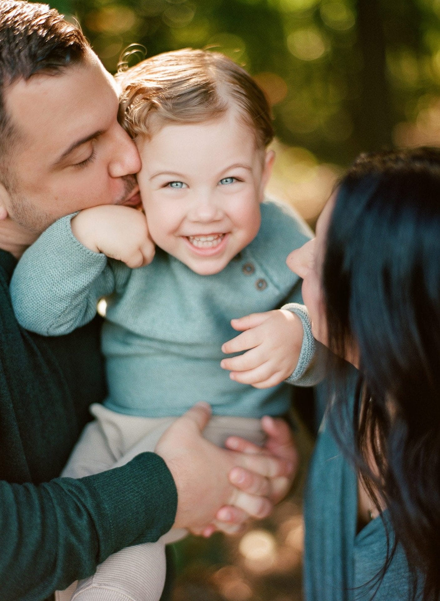 A mom and dad pressed in close on either side of their laughing son during a family session in Mount Laurel, New Jersey