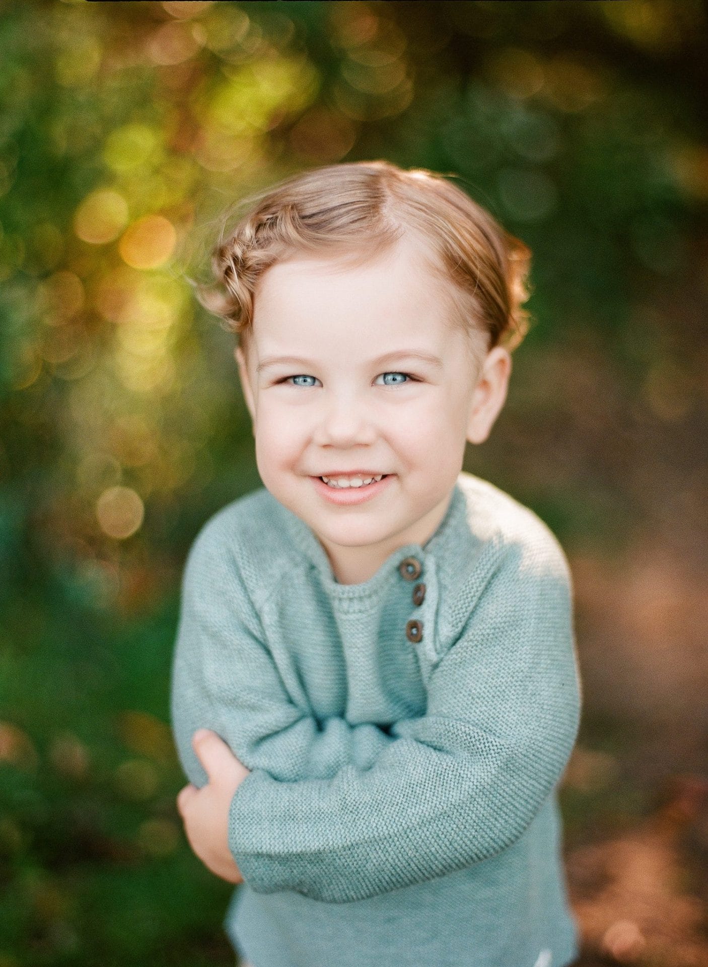 A portrait of a small boy with his arms folded in front of him under the trees in Mount Laurel, New Jersey