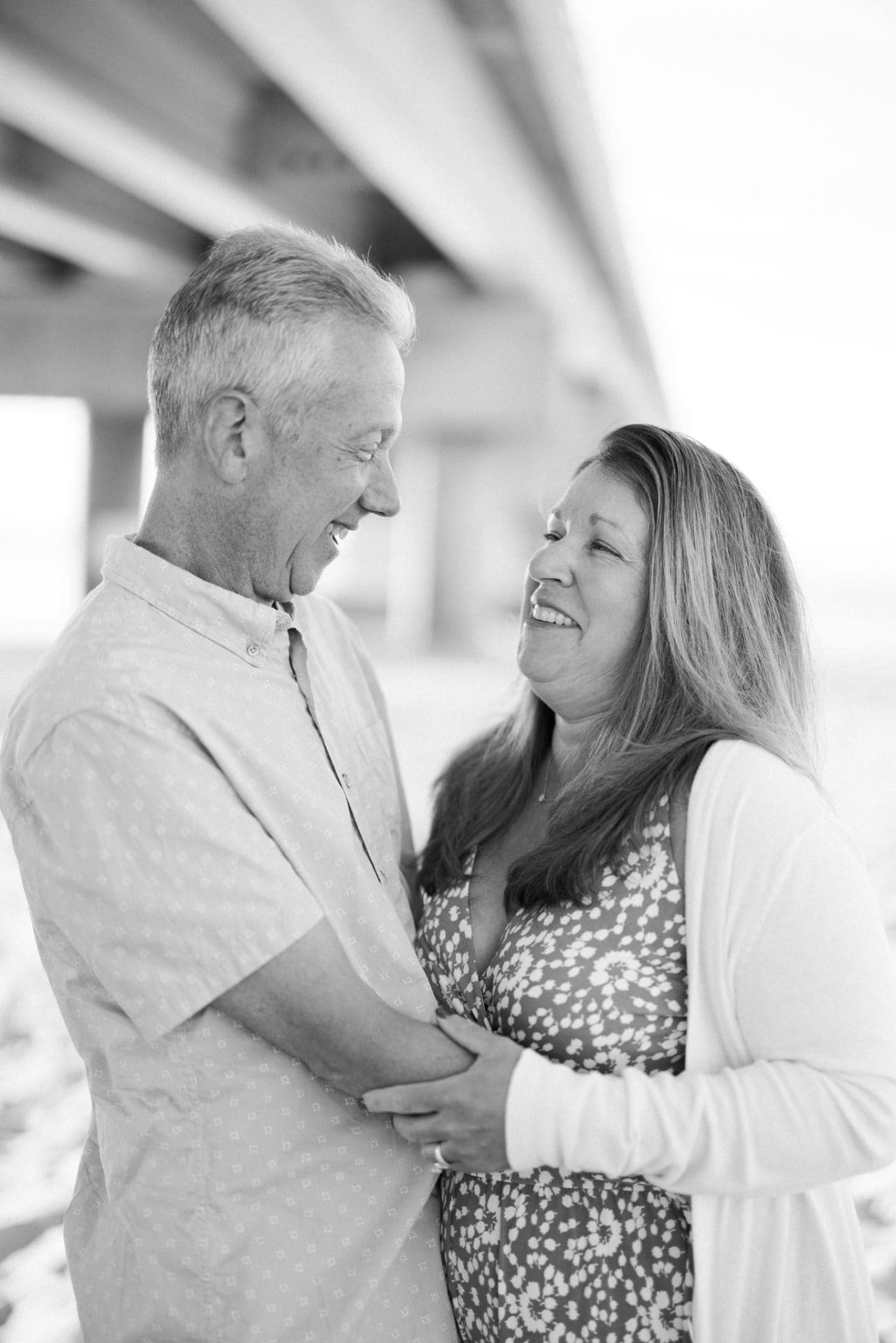 A black and white photograph of a mom and dad laughing together during a family session in Ocean City, New Jersey