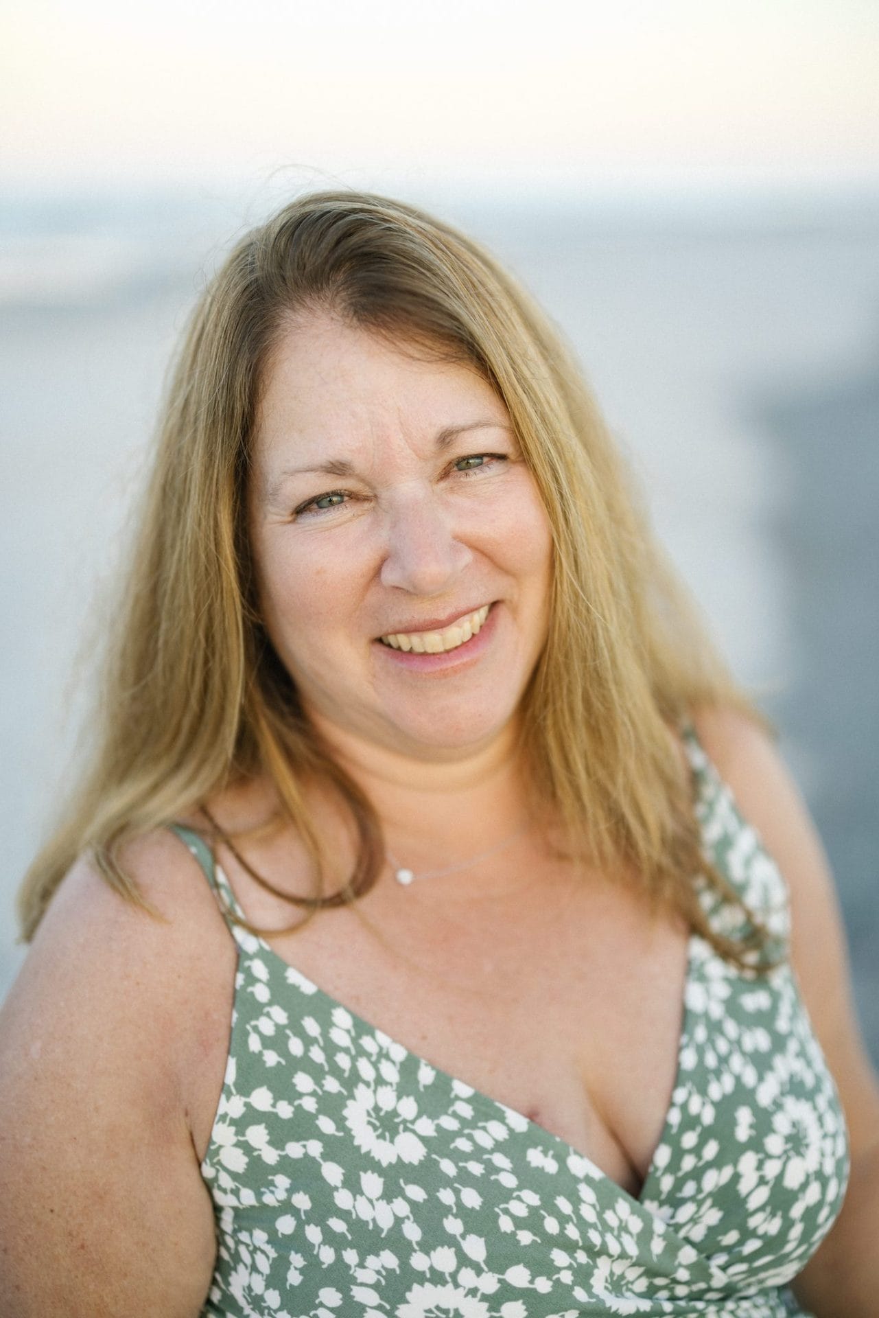 An individual portrait of a laughing woman in a green and white floral dress on the beach in Ocean City, New Jersey