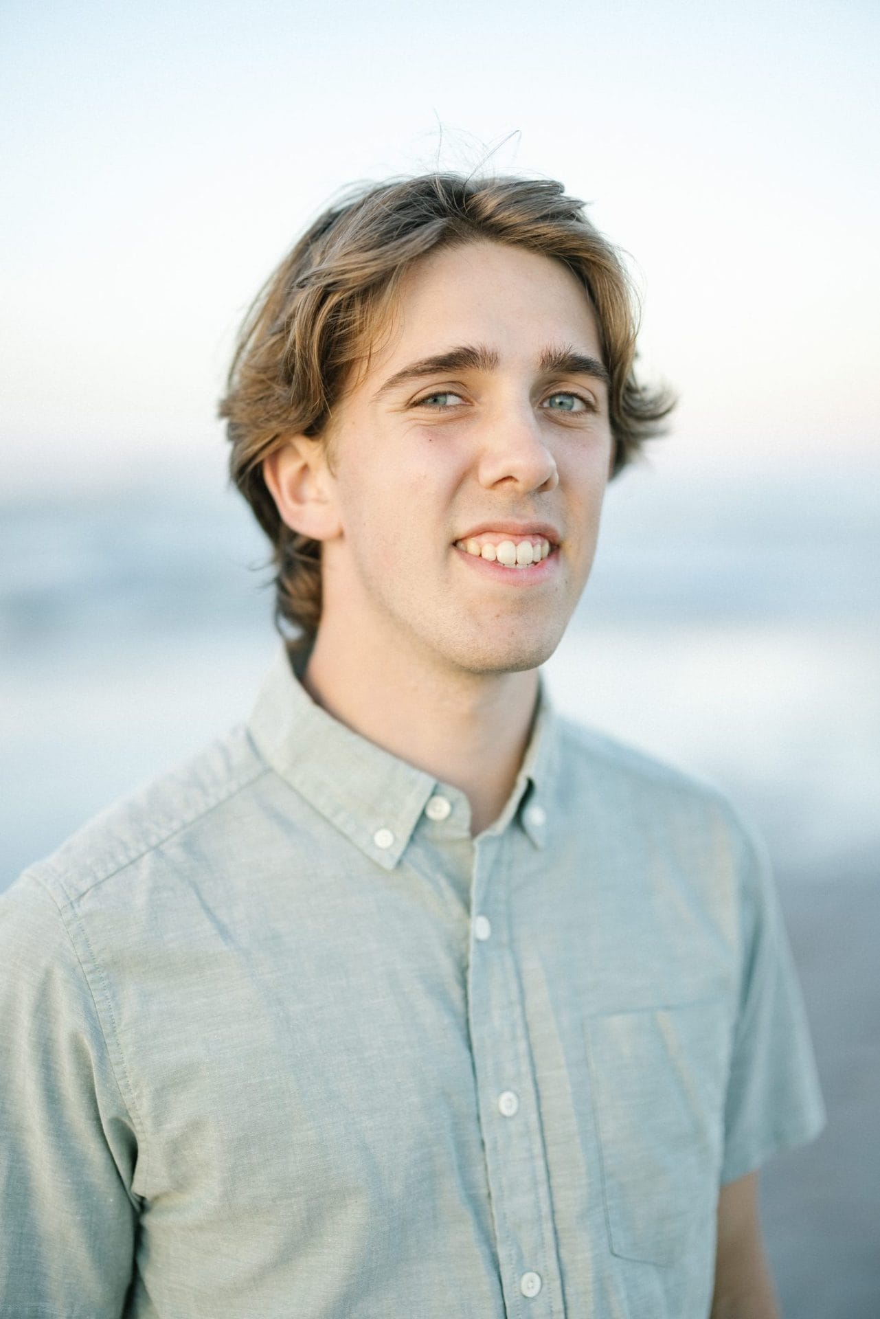 An individual portrait of a young man in a chambray button down shirt on the beach in Ocean City, New Jersey