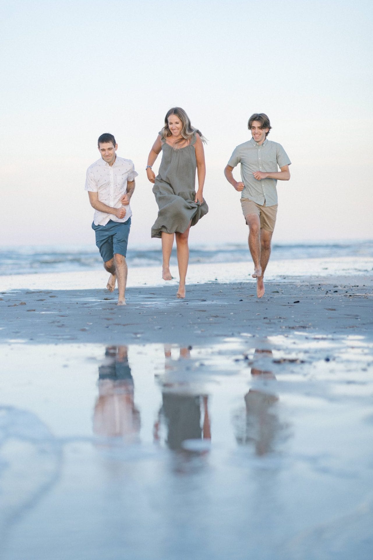 Three family members running barefoot back toward the camera across the wet sand in Ocean City, New Jersey