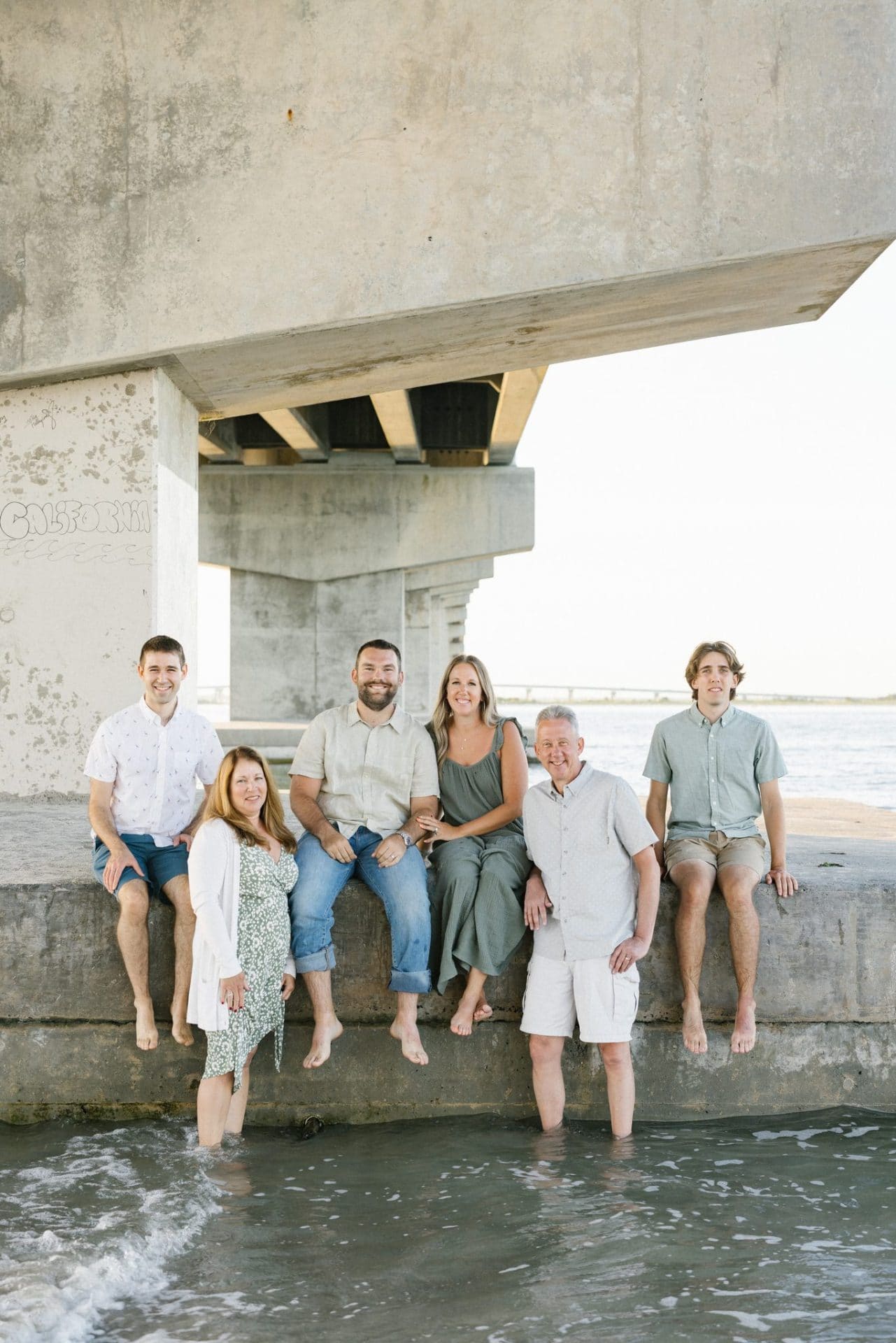 Four family members sitting along a concrete ledge with a mom and dad standing in the shallow water below them in Ocean City, New Jersey