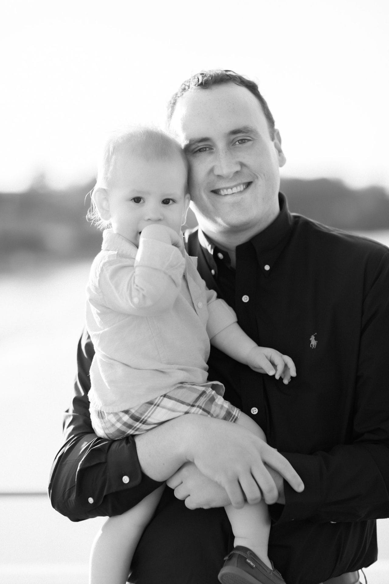A black and white photograph of a dad holding his son with both of them looking at the camera at the Philadelphia Water Works