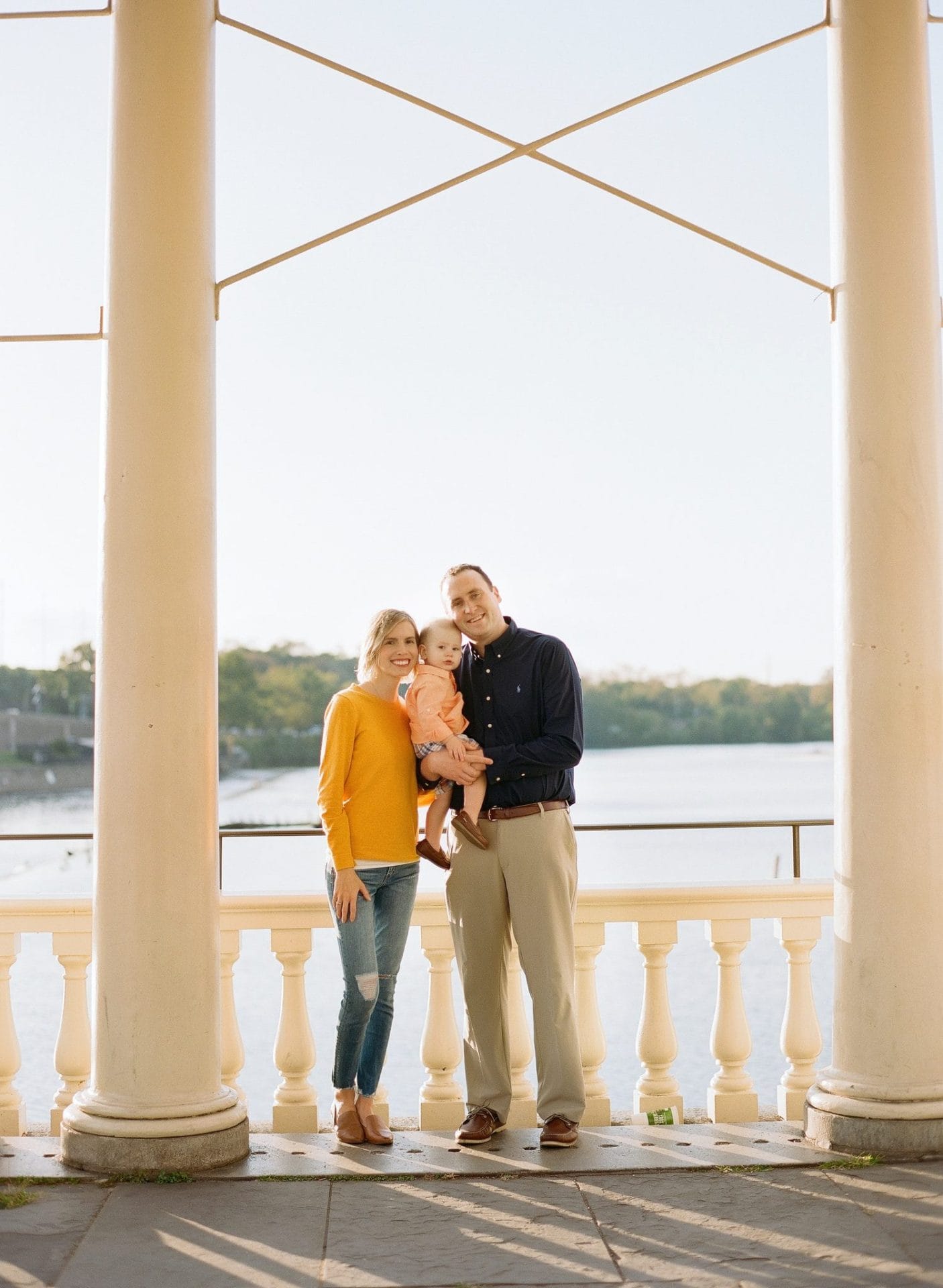 A family standing between two tall columns at the Fairmount Water Works with the Schuylkill River behind them
