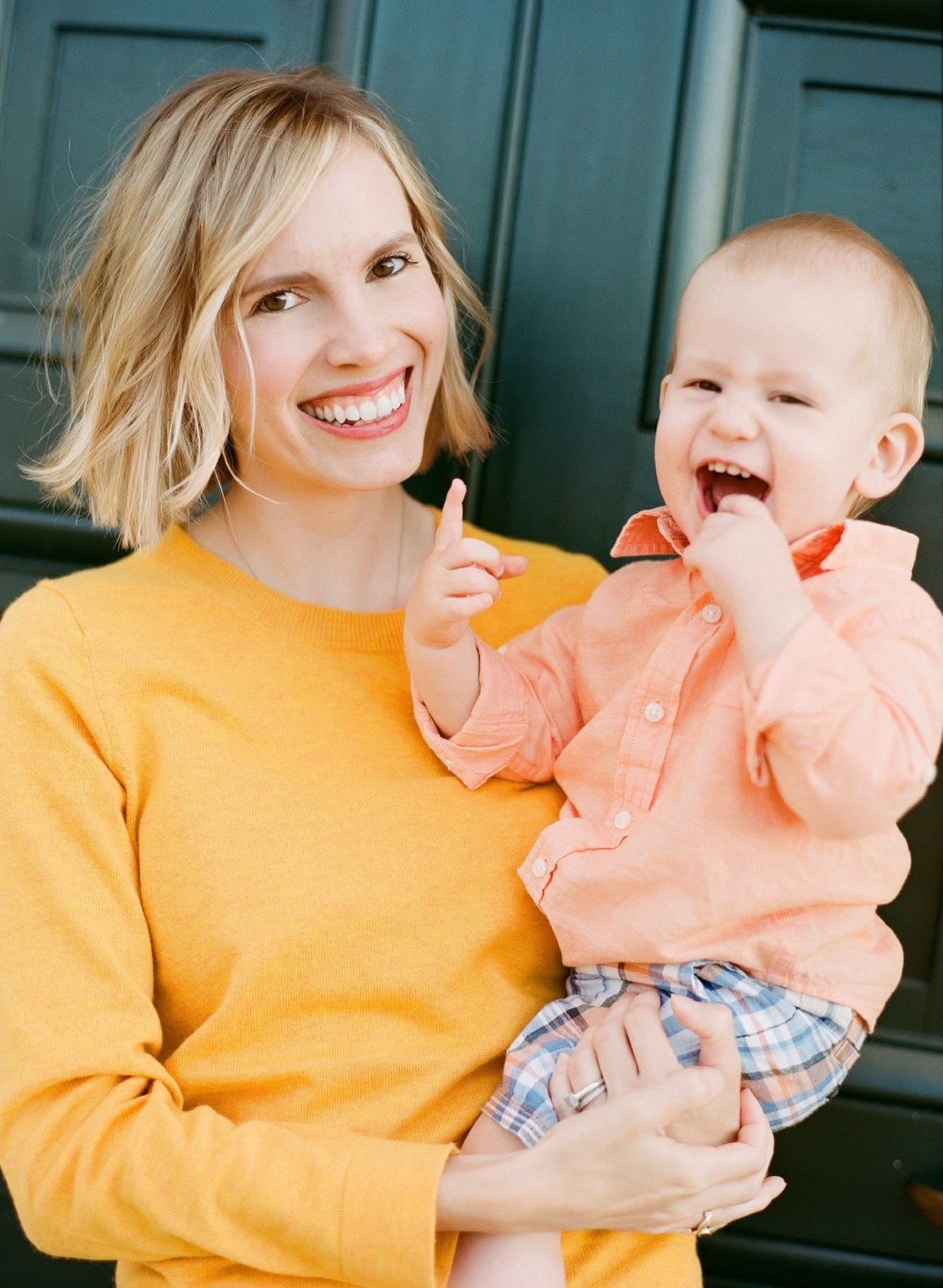A mom and her son both laughing at the camera against a green door during a family session at the Philadelphia Water Works