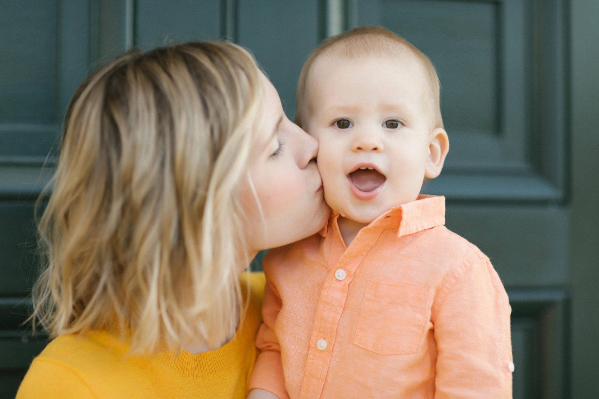 A mom kissing her son's cheek in front of a green door at the Fairmount Water Works in Philadelphia